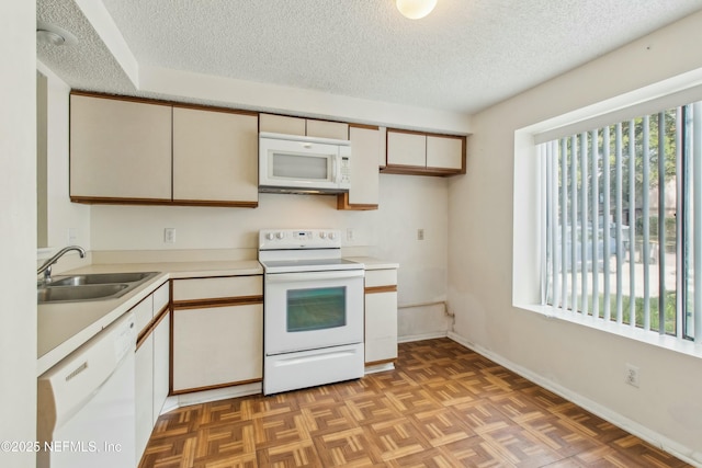 kitchen featuring a textured ceiling, white appliances, a sink, baseboards, and light countertops