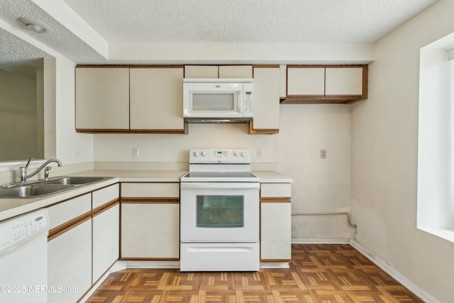 kitchen featuring a textured ceiling, white appliances, a sink, baseboards, and light countertops