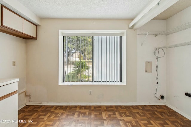 laundry room featuring a textured ceiling, cabinet space, and baseboards