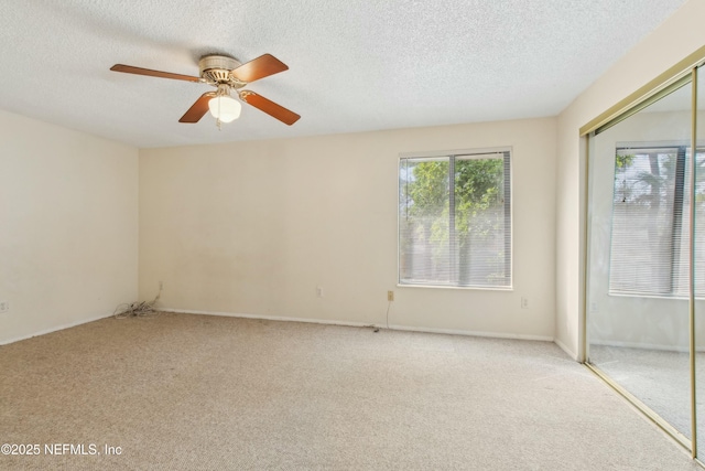 empty room featuring light colored carpet, ceiling fan, and a textured ceiling