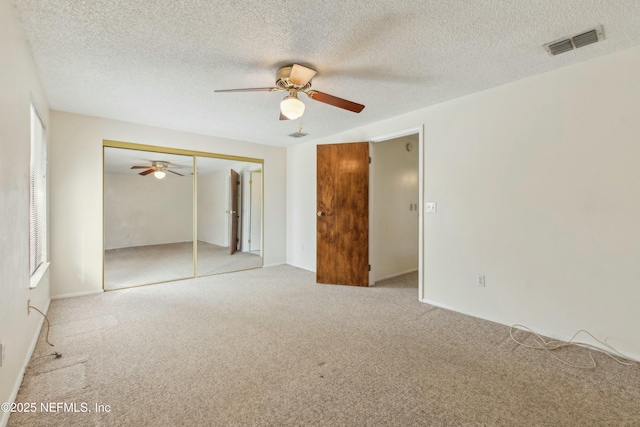 unfurnished bedroom with carpet, a closet, visible vents, a ceiling fan, and a textured ceiling