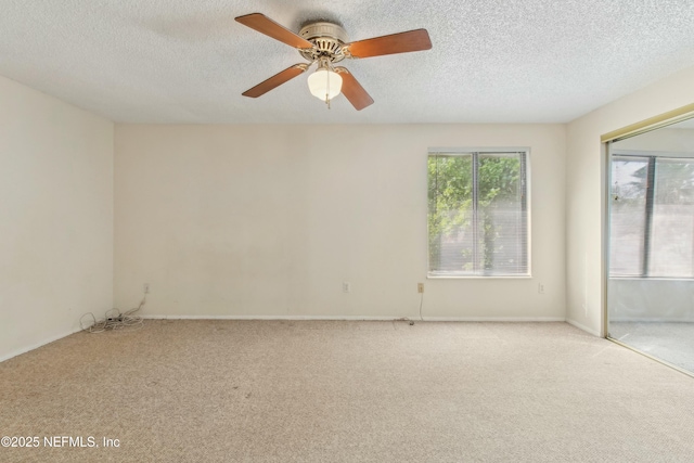 spare room with a textured ceiling, carpet flooring, and a ceiling fan