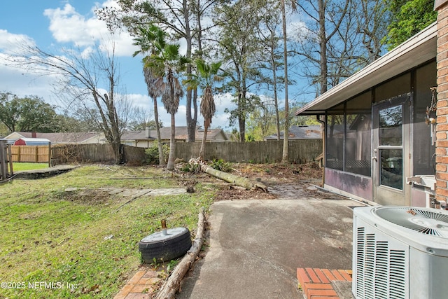 view of yard with central air condition unit, a sunroom, a fenced backyard, and a patio