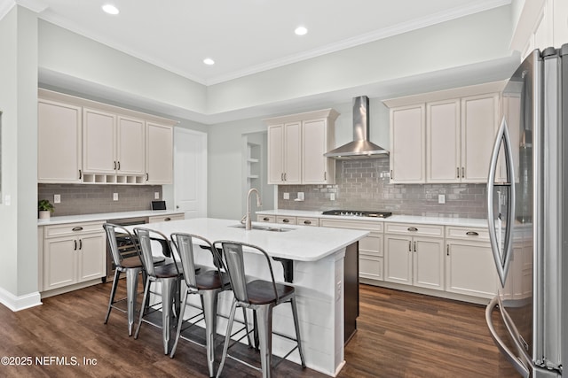 kitchen featuring dark wood finished floors, freestanding refrigerator, a sink, light countertops, and wall chimney range hood