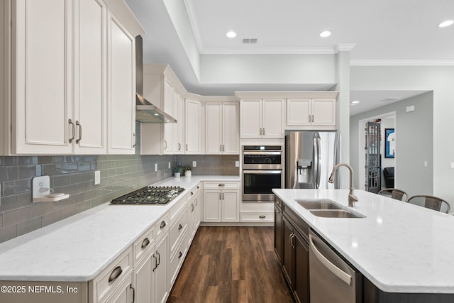 kitchen featuring dark wood-style floors, a sink, appliances with stainless steel finishes, wall chimney range hood, and backsplash