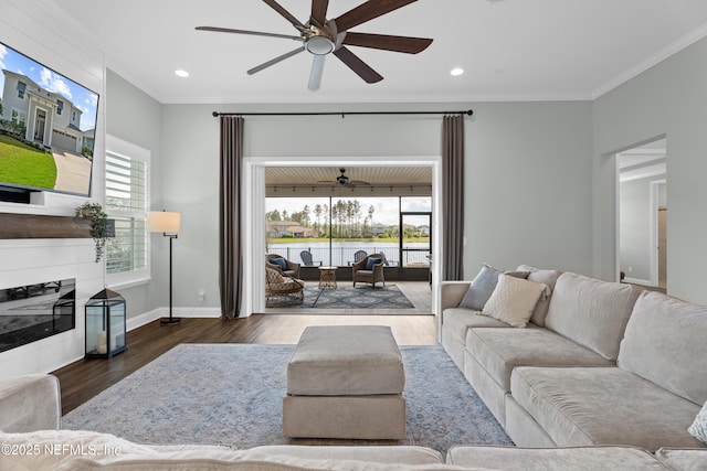 living room with a glass covered fireplace, crown molding, baseboards, and wood finished floors