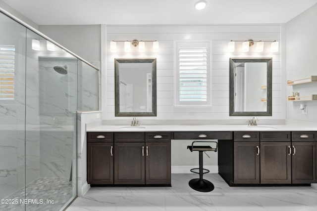 full bathroom with double vanity, a marble finish shower, marble finish floor, and a sink