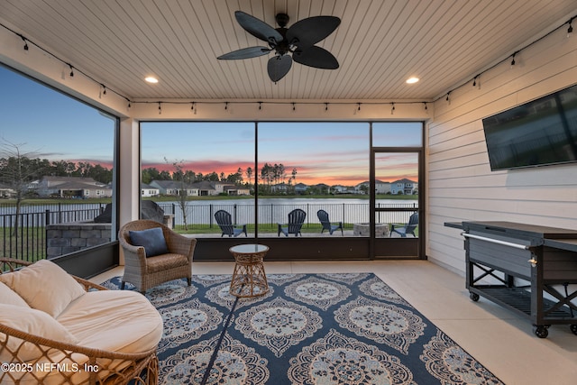 sunroom / solarium featuring plenty of natural light, rail lighting, wood ceiling, and a ceiling fan