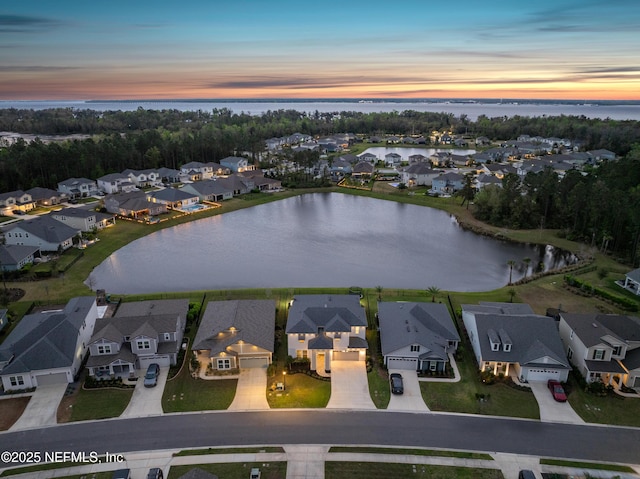 aerial view at dusk featuring a residential view and a water view