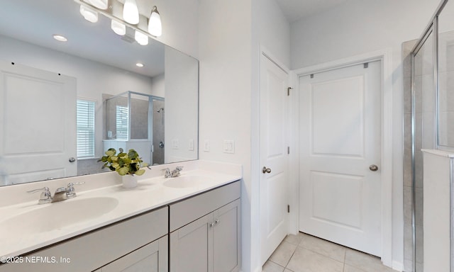 full bath featuring double vanity, a shower stall, a sink, and tile patterned floors