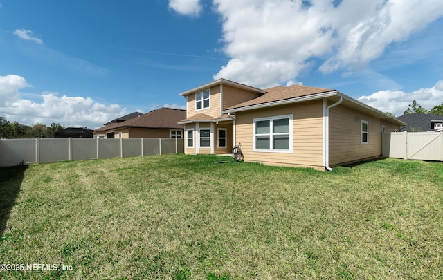 rear view of house with a fenced backyard and a lawn