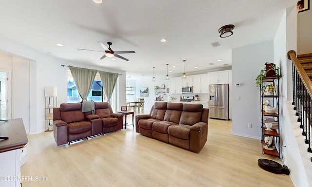 living room with ceiling fan, stairway, light wood-style flooring, and recessed lighting