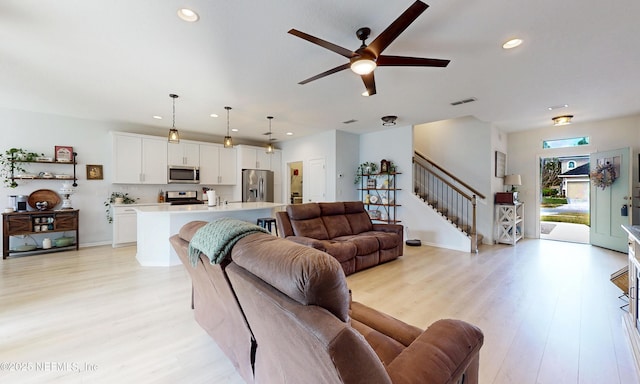 living area featuring visible vents, baseboards, light wood-style flooring, stairway, and recessed lighting