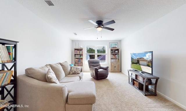 living room featuring visible vents, light colored carpet, a ceiling fan, a textured ceiling, and baseboards