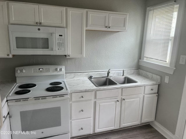 kitchen with white appliances, white cabinets, and a sink