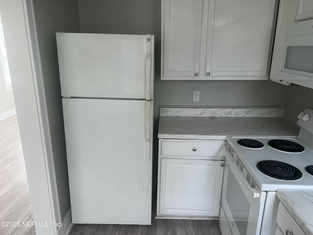 kitchen with white appliances, white cabinetry, and light stone counters