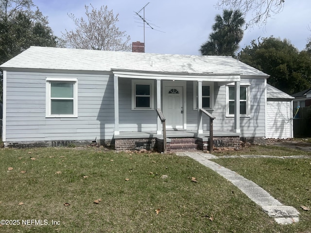 view of front of house with covered porch, a chimney, and a front yard