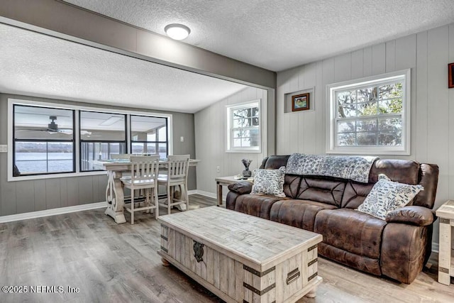 living area with a textured ceiling, light wood finished floors, and baseboards