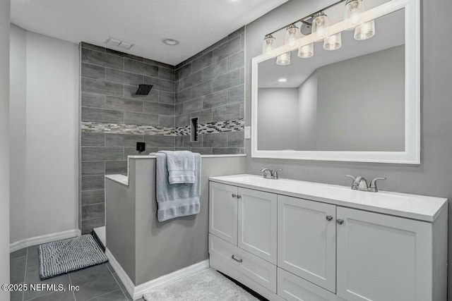 bathroom with baseboards, double vanity, walk in shower, and tile patterned floors