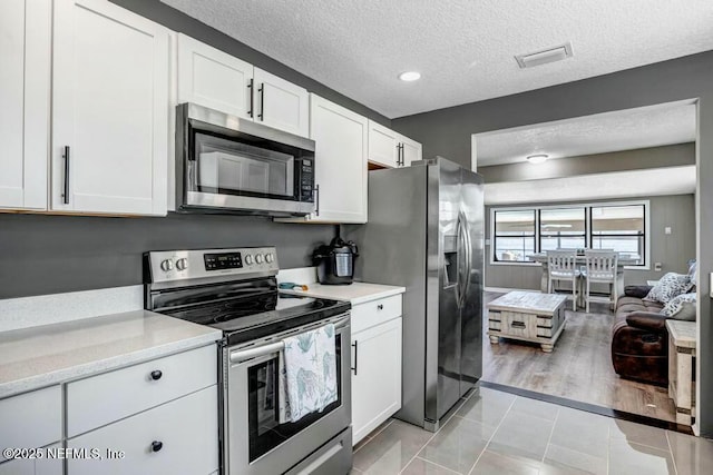 kitchen featuring appliances with stainless steel finishes, white cabinetry, visible vents, and a textured ceiling