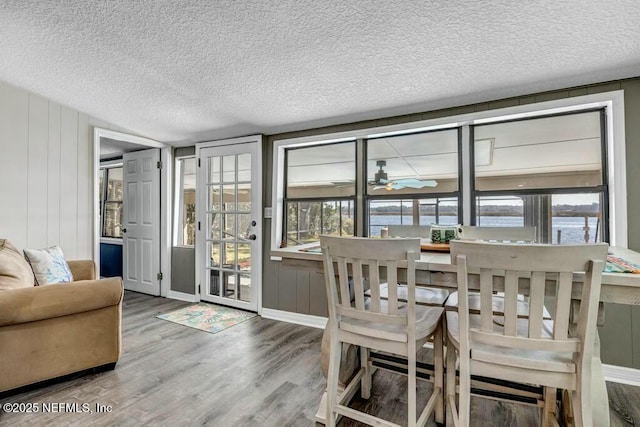 dining space featuring ceiling fan, a textured ceiling, and wood finished floors