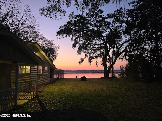 yard at dusk featuring a water view