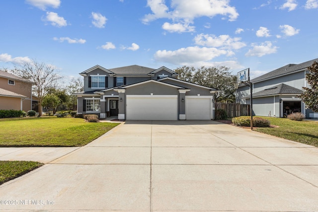 traditional-style home featuring a garage, driveway, fence, a front lawn, and stucco siding