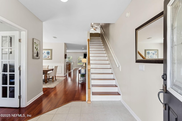 tiled foyer entrance featuring stairway and baseboards