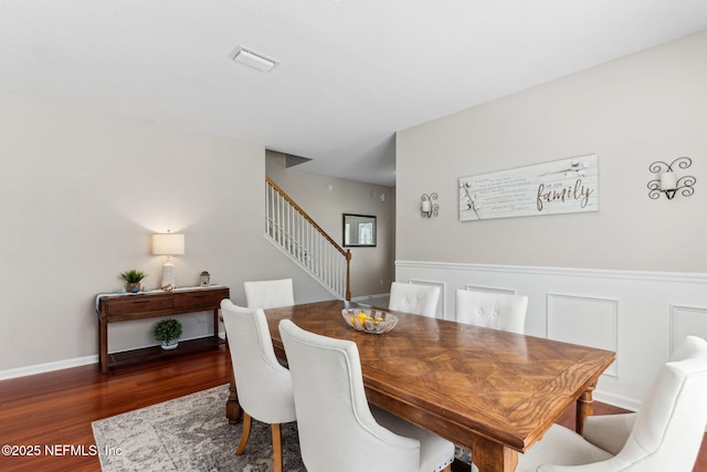 dining room featuring stairs, wainscoting, wood finished floors, and visible vents