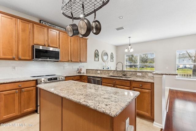 kitchen featuring stainless steel appliances, visible vents, a sink, a kitchen island, and a peninsula