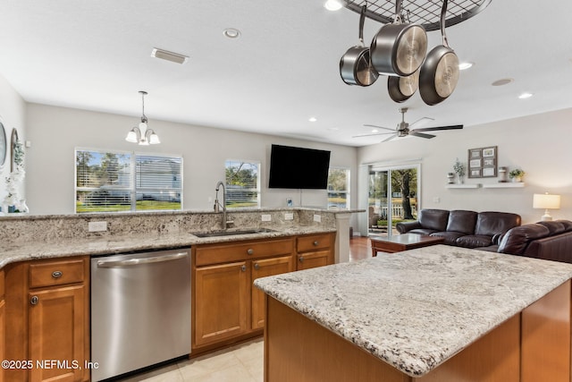 kitchen featuring dishwasher, brown cabinetry, open floor plan, and a sink