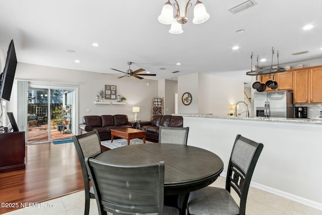 dining space with light tile patterned floors, ceiling fan with notable chandelier, visible vents, and recessed lighting