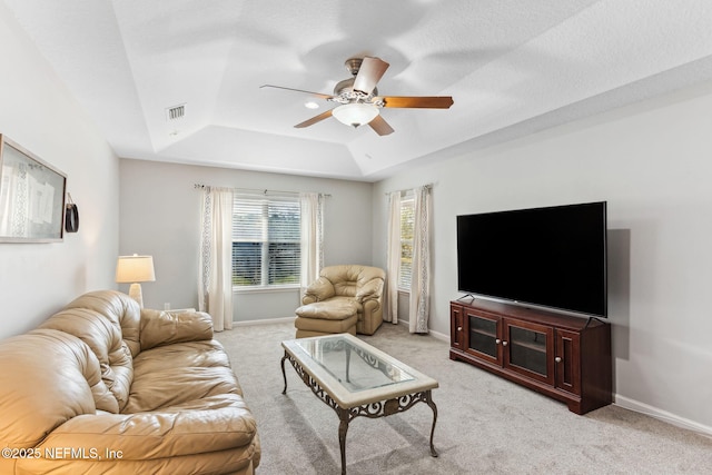 living area with baseboards, a tray ceiling, a ceiling fan, and light colored carpet