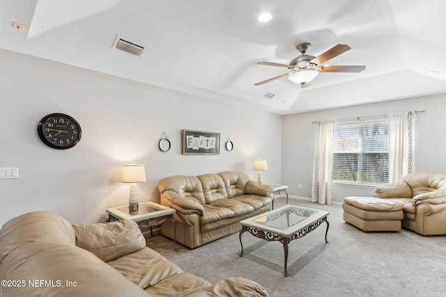 carpeted living room featuring ceiling fan, a raised ceiling, visible vents, and baseboards