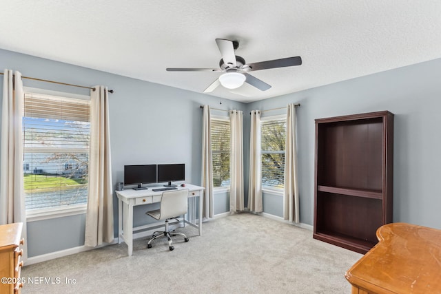 carpeted office space featuring ceiling fan, baseboards, and a textured ceiling