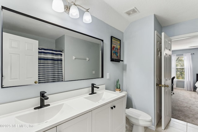 bathroom featuring visible vents, a sink, toilet, and double vanity