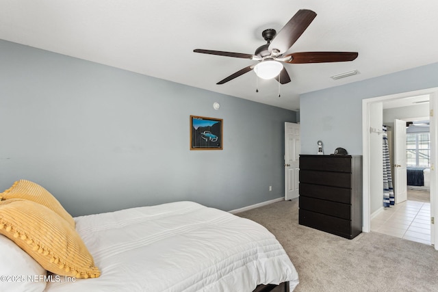 bedroom with ceiling fan, light tile patterned floors, light carpet, visible vents, and baseboards