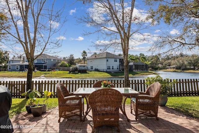 view of patio featuring a water view, a residential view, fence, and outdoor dining space