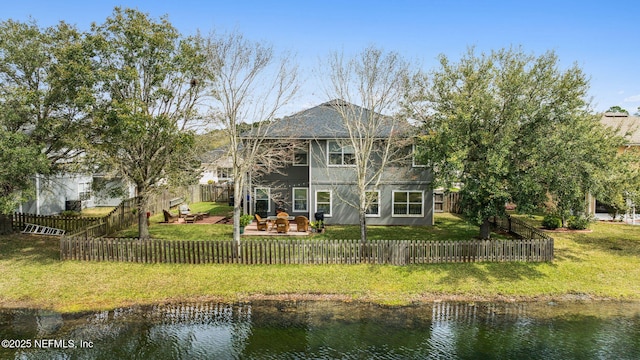 rear view of house featuring a yard, a fenced front yard, and a deck with water view