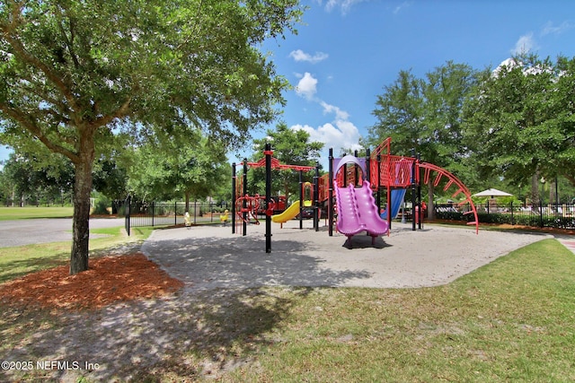 communal playground featuring a yard and fence