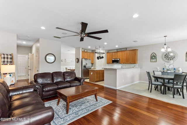 living room featuring a ceiling fan, recessed lighting, baseboards, and wood finished floors