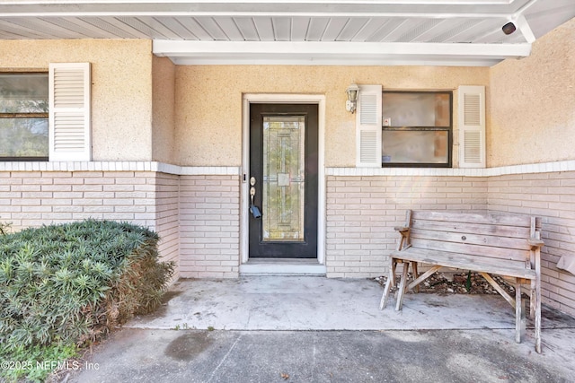 view of exterior entry featuring brick siding