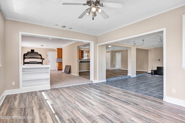 empty room with crown molding, visible vents, ceiling fan, wood finished floors, and baseboards