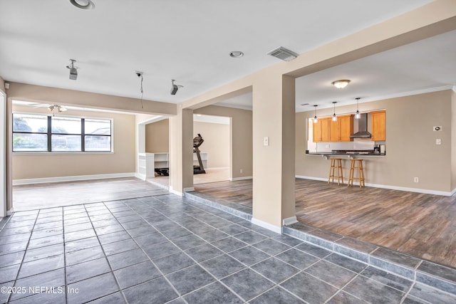 unfurnished living room featuring ornamental molding, dark wood-style flooring, visible vents, and baseboards