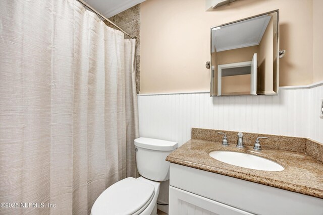 bathroom featuring a wainscoted wall, vanity, toilet, and a shower with curtain