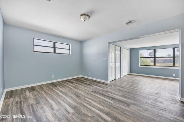 empty room featuring plenty of natural light, baseboards, and wood finished floors