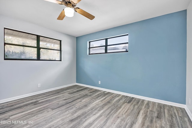 spare room featuring ceiling fan, plenty of natural light, baseboards, and wood finished floors