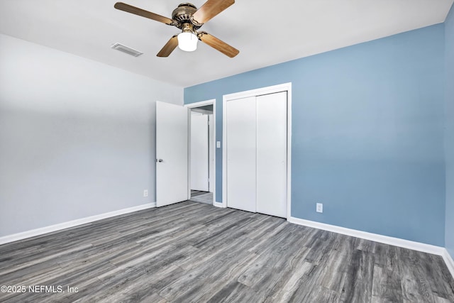 unfurnished bedroom with ceiling fan, wood finished floors, visible vents, baseboards, and a closet