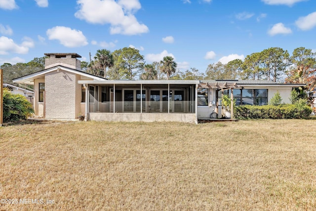 back of house with a yard, a chimney, and a sunroom