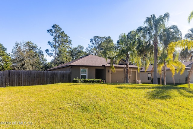 view of front of home with a front yard, fence, an attached garage, and stucco siding